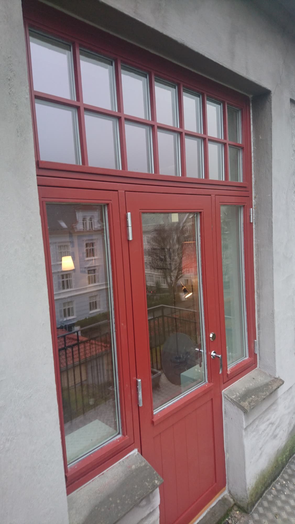 Rød inngangsdør med sprossevinduer og overlys